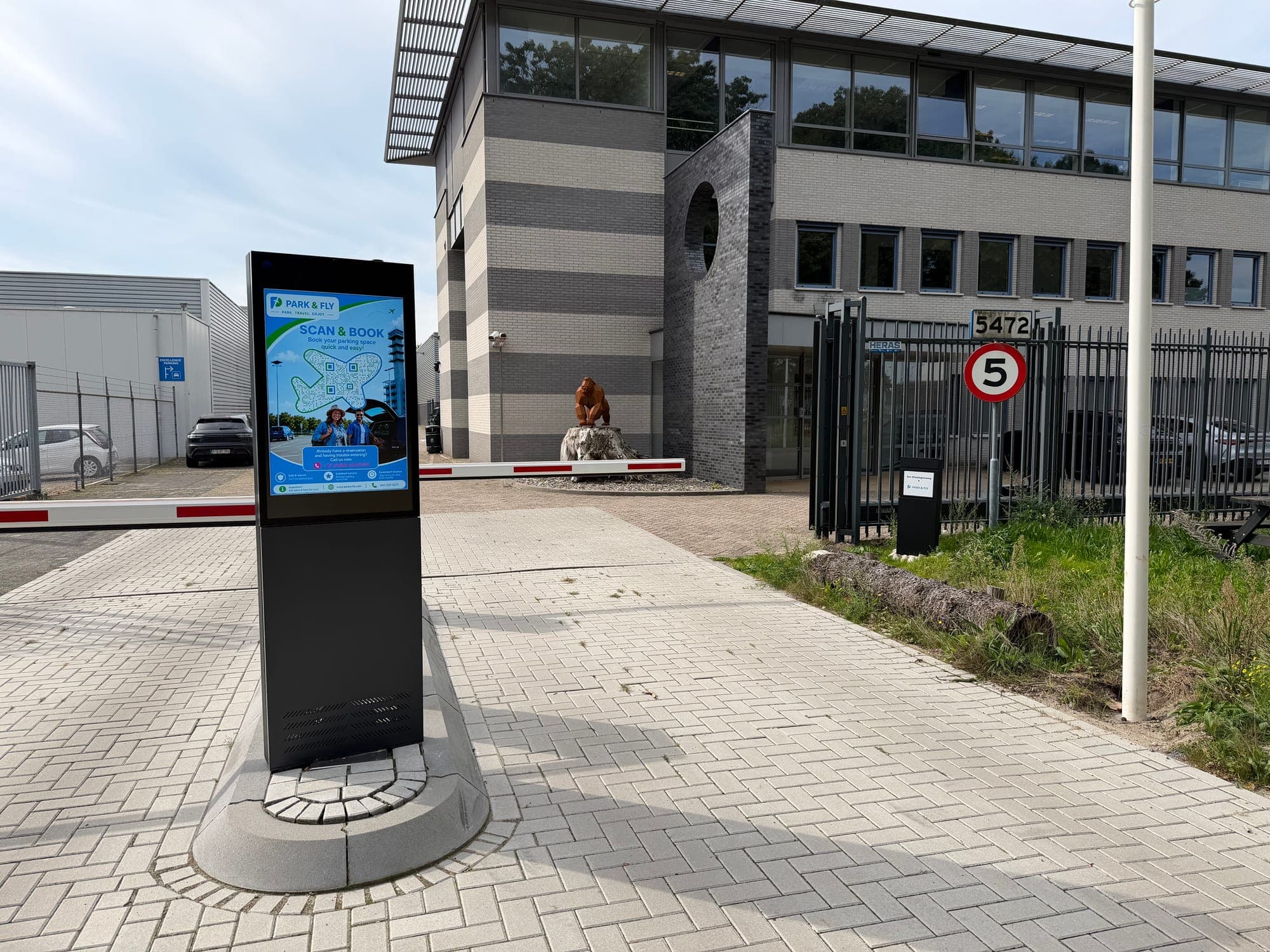 Die Einfahrt von Park en Fly P21 am Flughafen Eindhoven: die Säule, an der du deine Buchung scannst, dahinter die Schranke und das Büro.