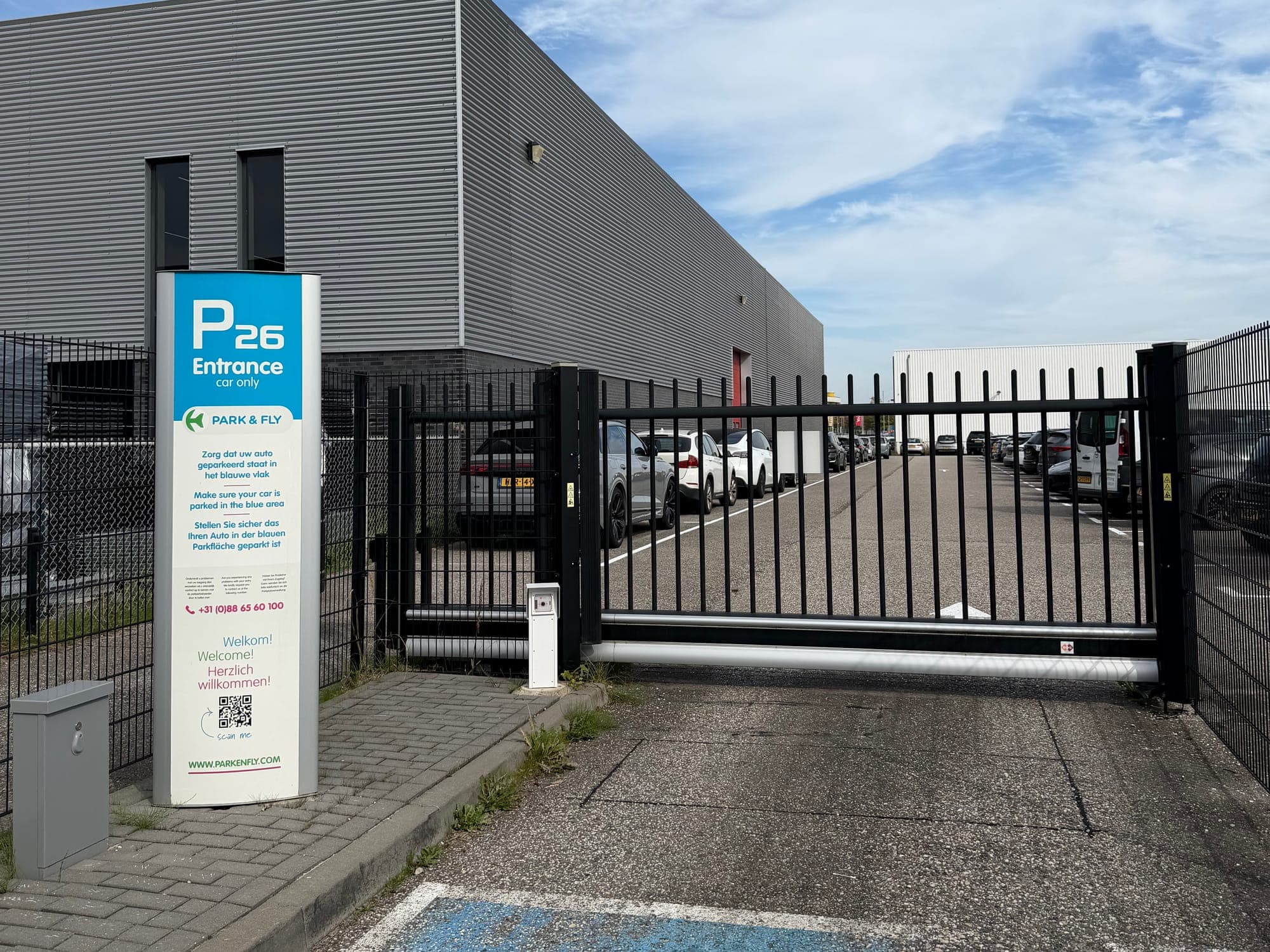 The "P26 Entrance" sign of Park en Fly at Eindhoven Airport next to the sliding gate of the car park.